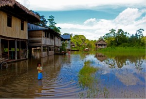 Niño junto a una casa típica del río Amazonas
