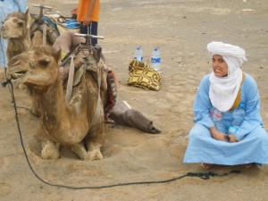 Viajera Faro en medio del desierto descansando con su camello y vestida con turbante.