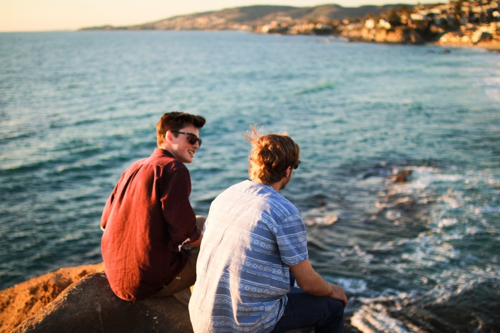 Amigos conversando sobre las rocas junto al mar
